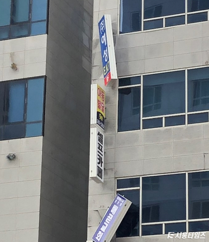 떨어지기 일보 직전으로 위태롭게 달린 간판 모습