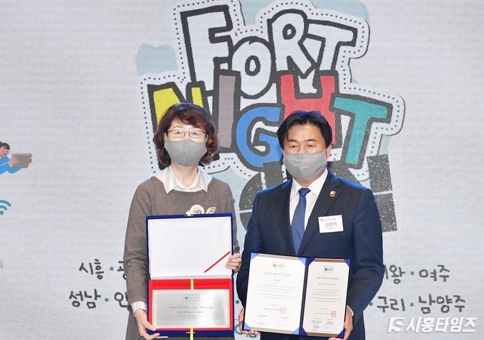 임병택 시흥시장이 한금희 한국공정무역마을위원회 위원장으로부터 공정무역 인증도시 인증서를 전달받았다. 지료제공: 시흥시